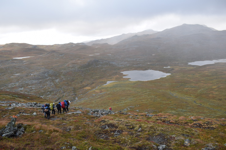 En grupp människor syns på håll i ett fjällandskap.