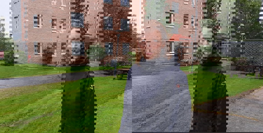 Jenny står framför ett hus i tegel. Hon har på sig en jacka där det står Vifab på ärmen.