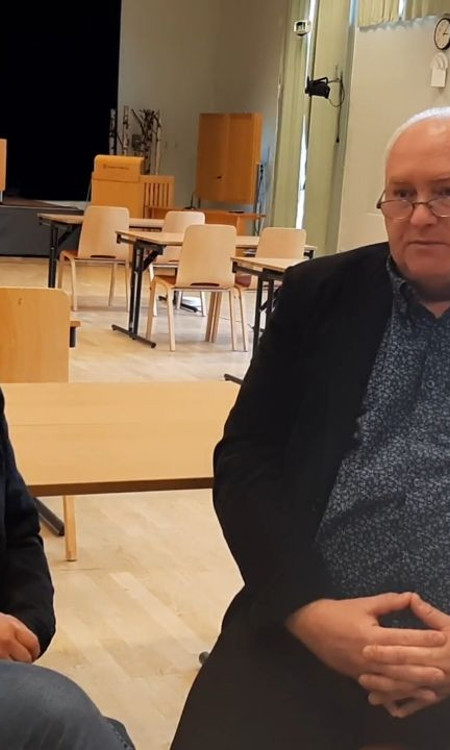 Två personer som sitter ner och samtalar med varandra.