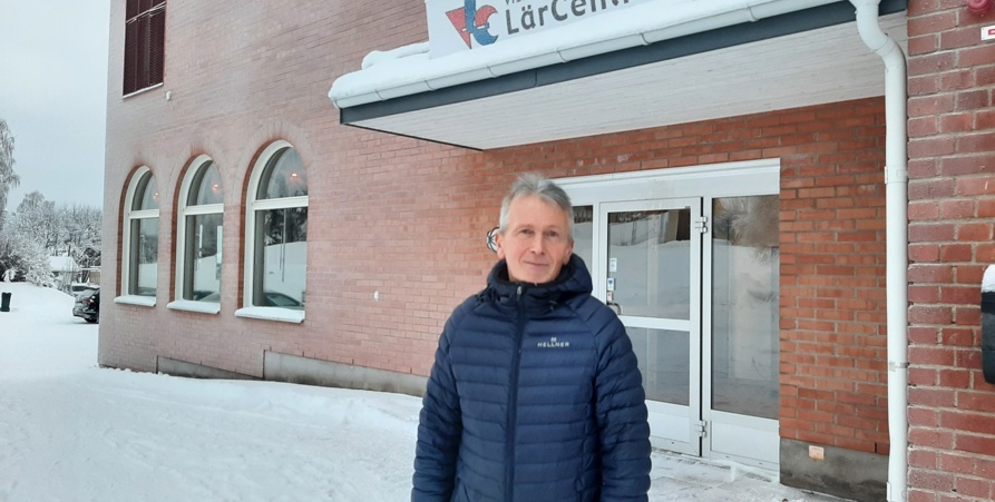 Lars Gavelin står framför ingången till byggnaden Lärcentrum. Han har på sig en blå dunjacka. Byggnaden är av rött tegel.